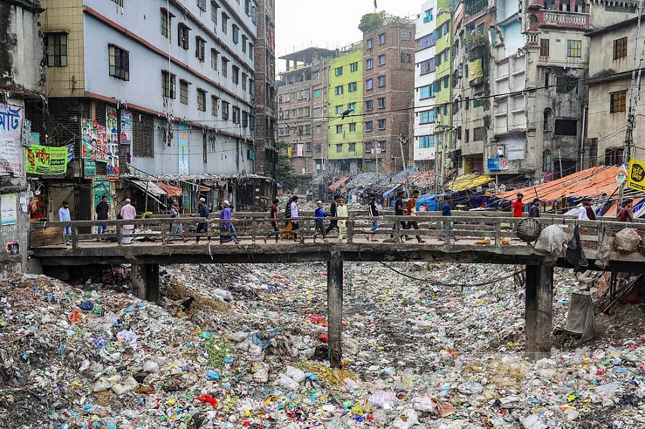 A stretch of Keraniganj’s Shubhadhya Canal lies buried beneath plastic waste, with people crossing the culvert above.